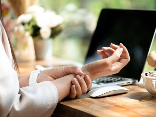 La sindrome del tunnel carpale è una patologia che comporta dolore alla mano: scopri cos'è! Donna si tocca la mano a causa di un dolore mentre è al pc