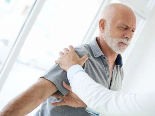 Medico visita uomo sofferente a causa di un dolore alla spalla